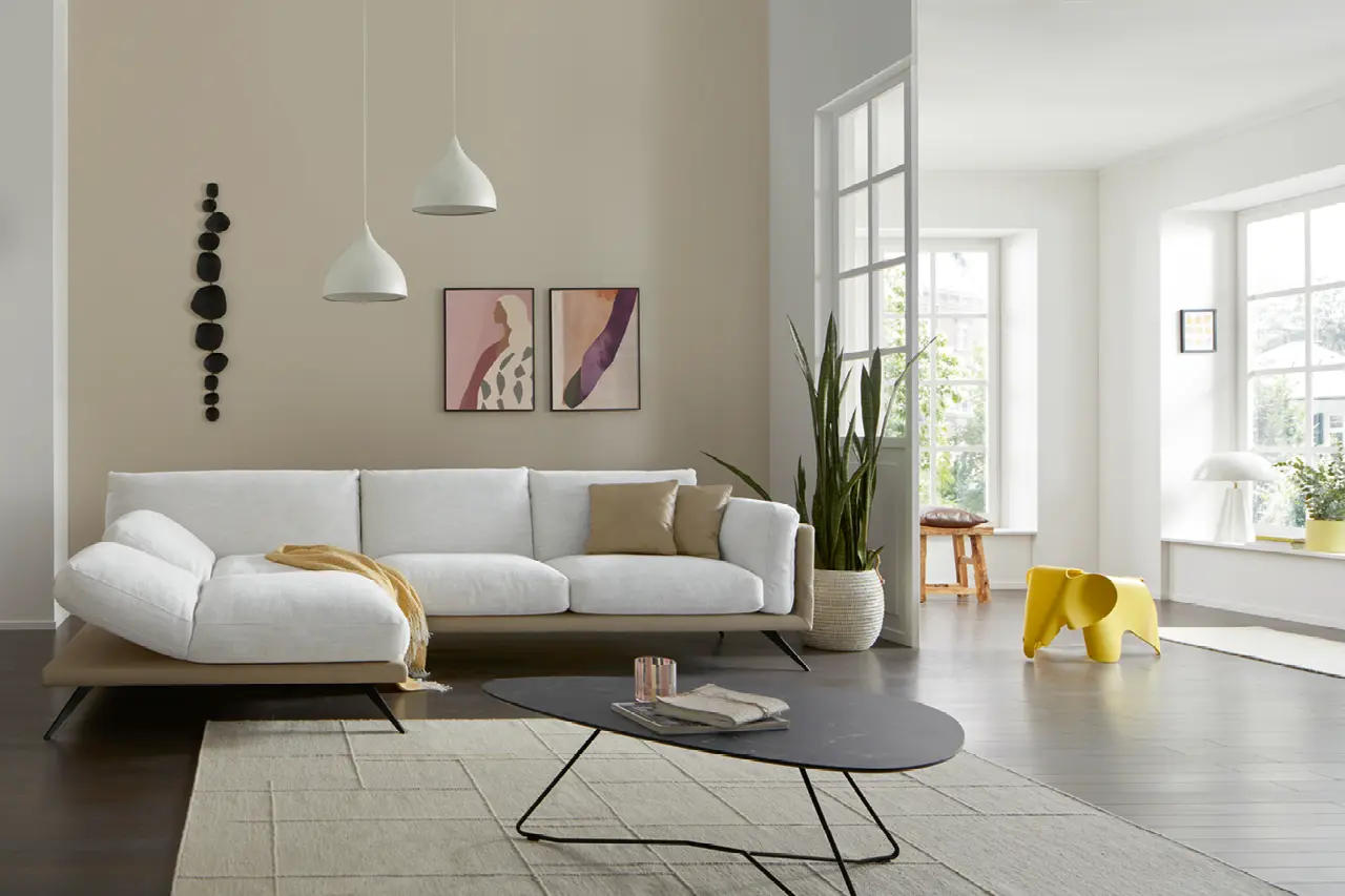 Helles modernes Wohnzimmer mit großem Ecksofa, minimalistischen Pendelleuchten, Couchtisch und dezenten Wohnaccessoires. Skandinavisches Wohnkonzept mit klaren Linien, viel Tageslicht und zeitloser Wohnmöbel Gestaltung.